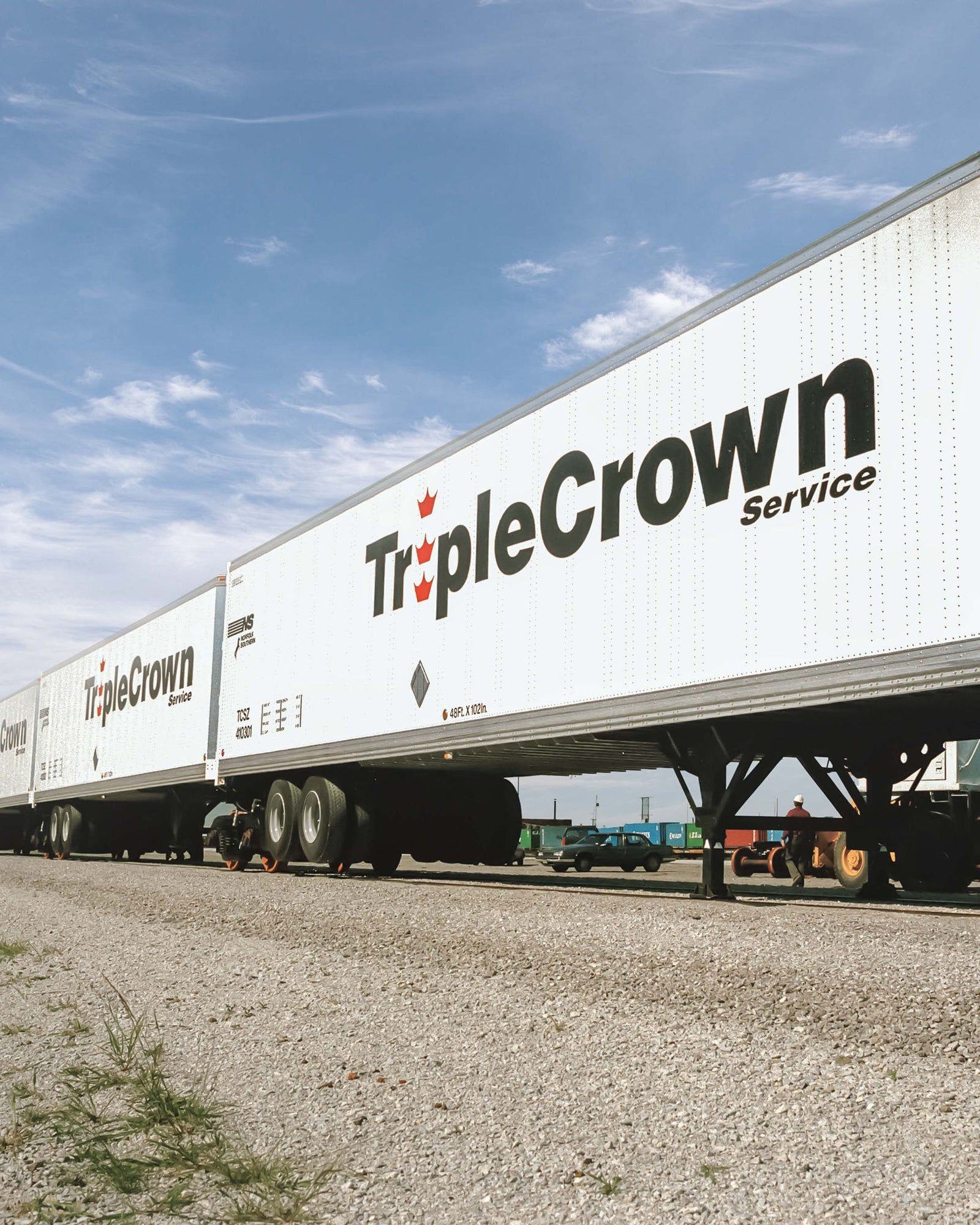 White TripleCrown Service semi-trailer parked on gravel under a blue sky