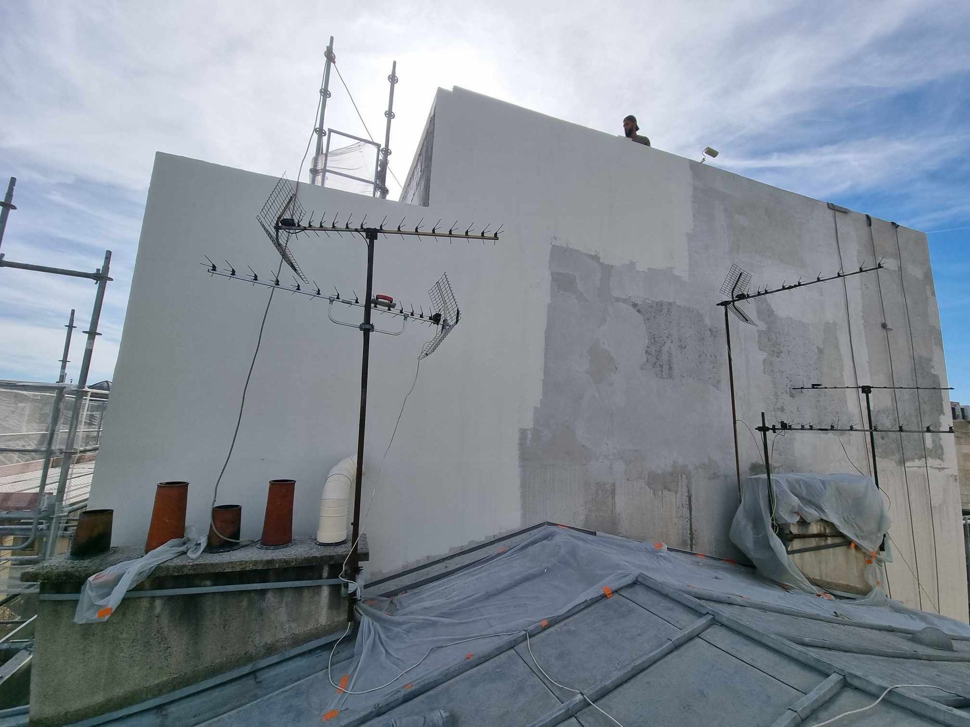 Un bâtiment avec un toit en train d'être peint et une antenne parabolique dessus.
