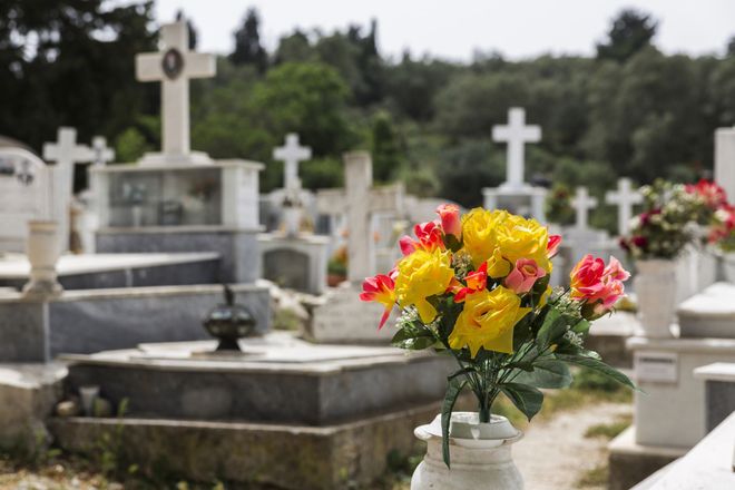 Mazzo di fiori rossi e gialli in un cimitero con croci e lapidi bianche.