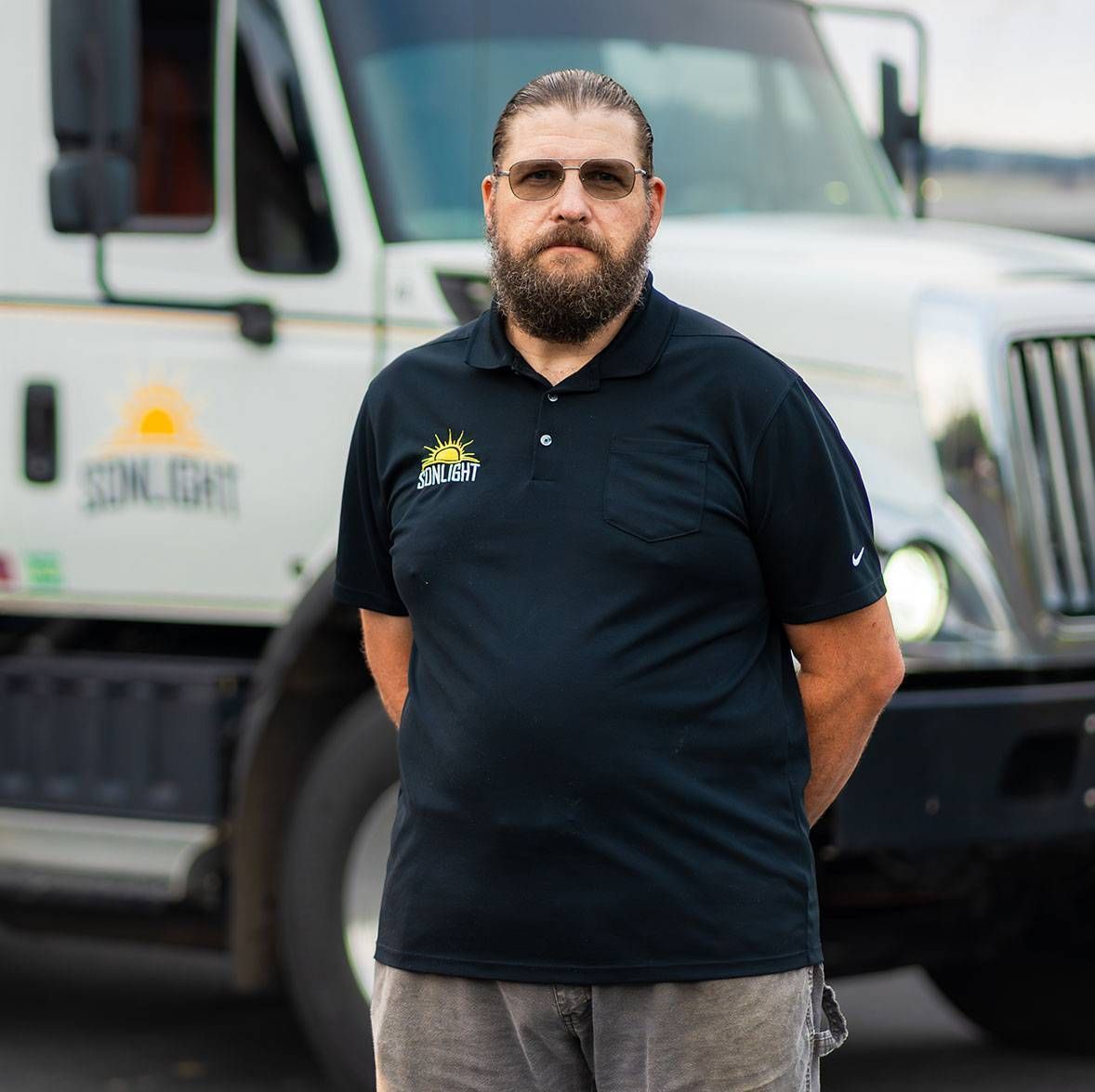 Matthew in a black polo standing in front of a white truck
