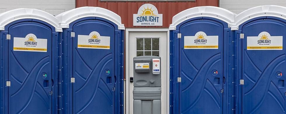Row of blue portable toilets with a gray handwashing station in the center