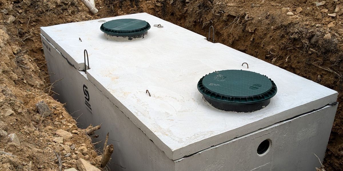 Rectangular metal tank in a dirt trench with two round green access covers