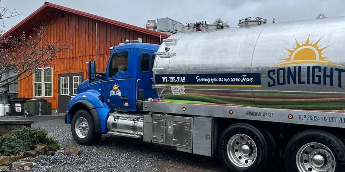 Blue tanker truck parked beside a wooden building in a snowy setting