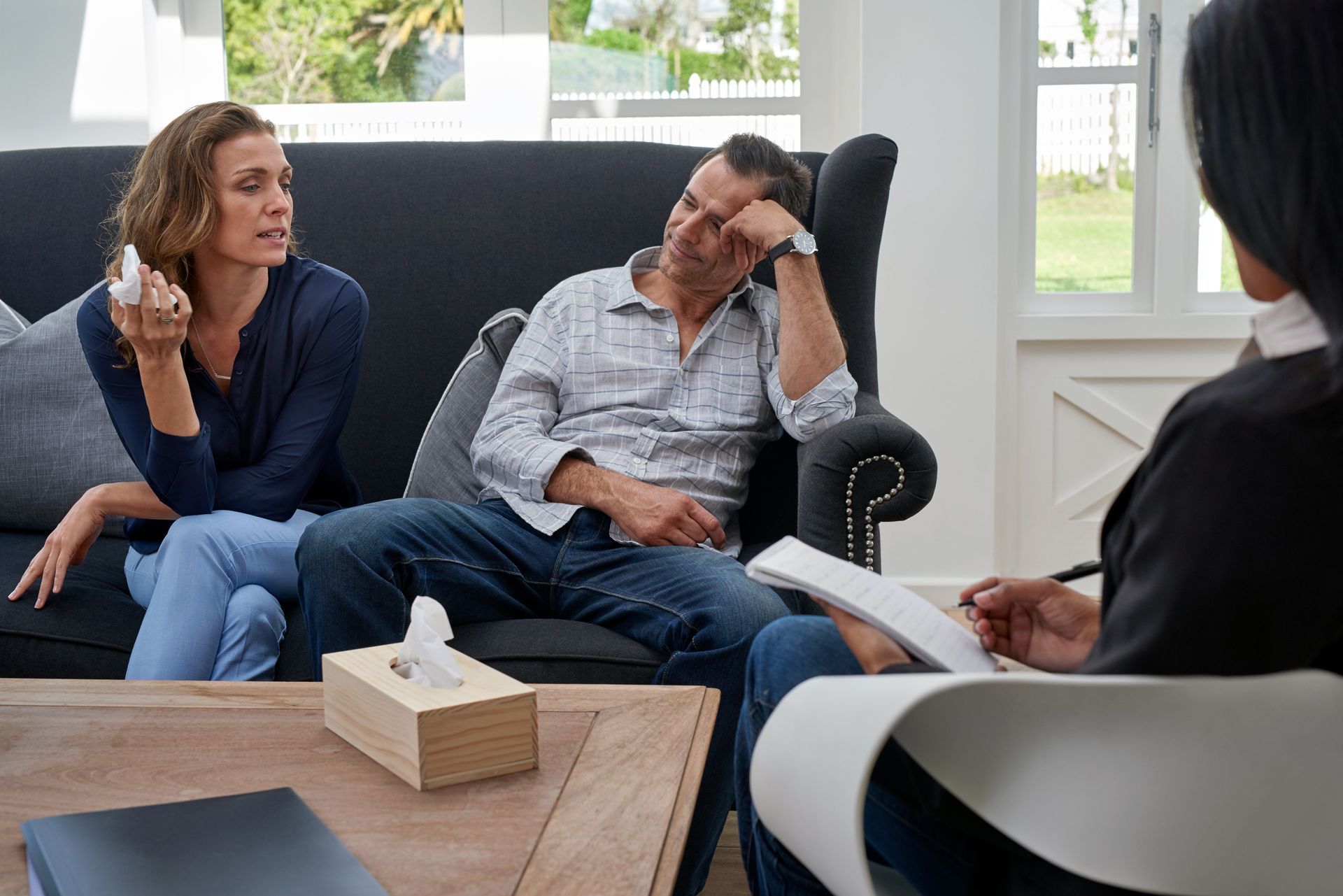 A man and a woman are sitting on a couch talking to a woman.