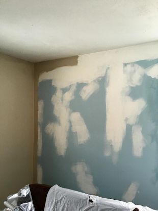 Partially painted room with blue drywall patches and white spackle on the walls