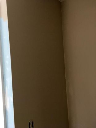 Empty beige wall corner with a narrow strip of white trim on the left