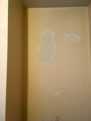 Beige interior wall with visible patchy paint repairs and scuff marks