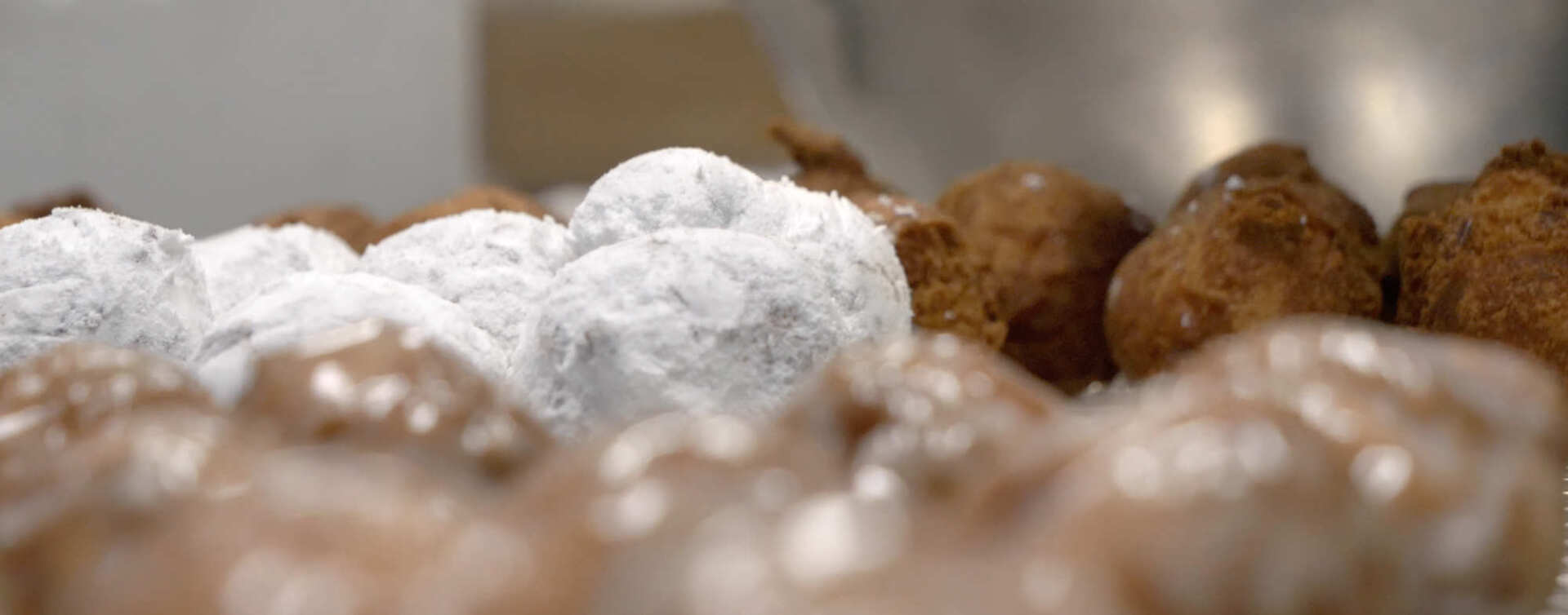 A bunch of doughnuts covered in powdered sugar are sitting on a table.