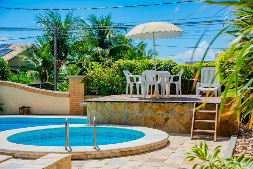Uma piscina com mesa e cadeiras e guarda-sol.