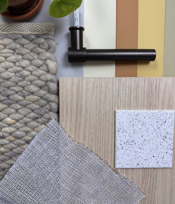 Materiaalstalen en een zwart handvat aan de muur, waarop stalen van hout, stof en gespikkelde materialen te zien zijn.