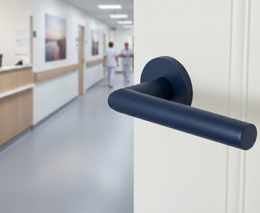 Donkerblauwe deurklink op een witte muur in een ziekenhuisgang met wazige figuren op de achtergrond.