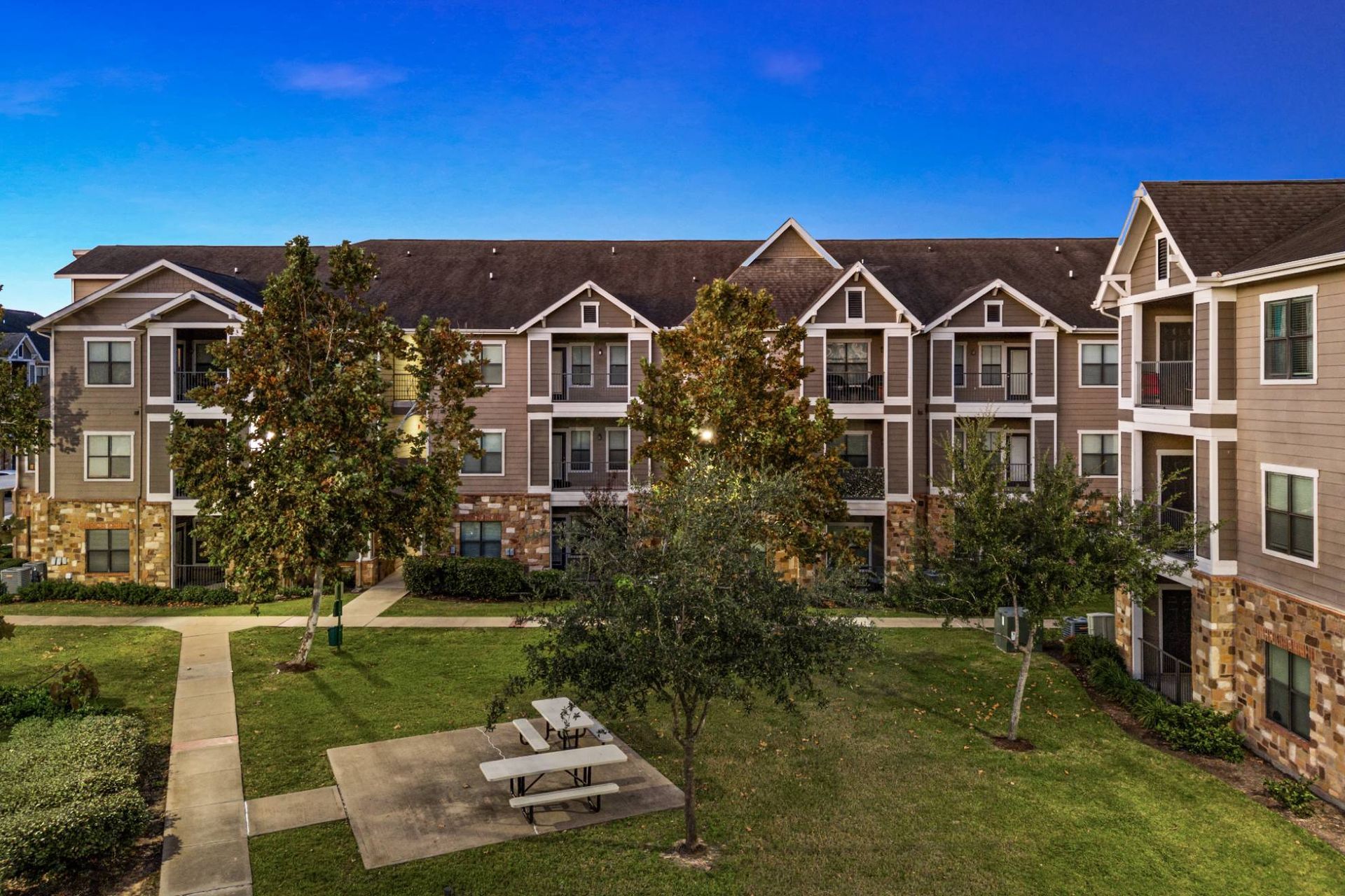 Exterior view of a multi-building apartment complex with a grassy courtyard.