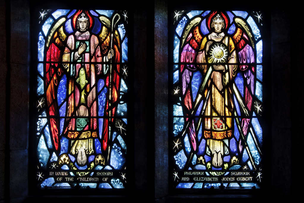 Two stained-glass windows depicting angels with colorful wings, surrounded by stars.