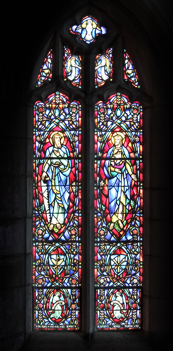 Stained-glass window depicting two figures, likely angels, in blue robes with halos, against a colorful background.
