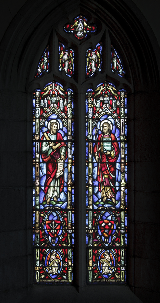 Stained glass window, two figures in red robes, blue background, arched top.