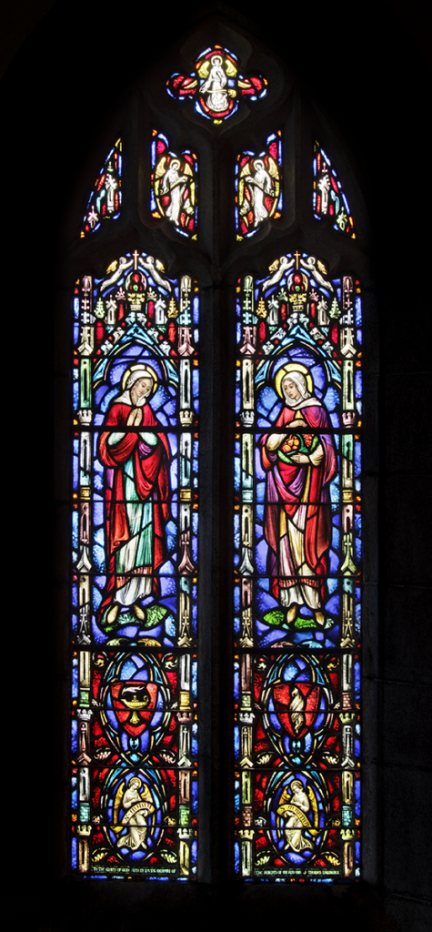 Stained glass window with two figures in red robes, surrounded by blue and red patterns.