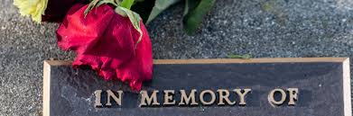 A tombstone with a red rose and 