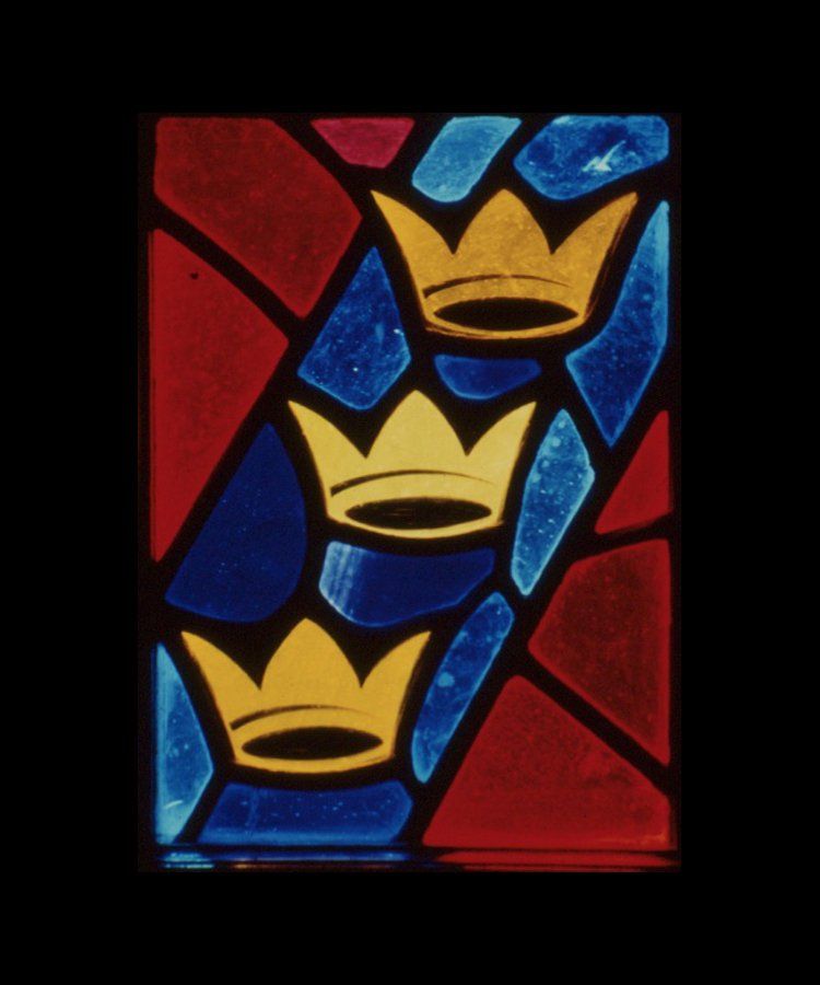 Stained glass panel with three gold crowns on a diagonal blue background, framed by red and dark glass.