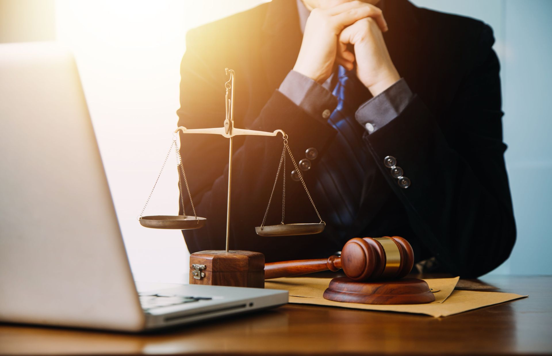 Lawyer at desk with laptop, scales of justice, and gavel in warm office light