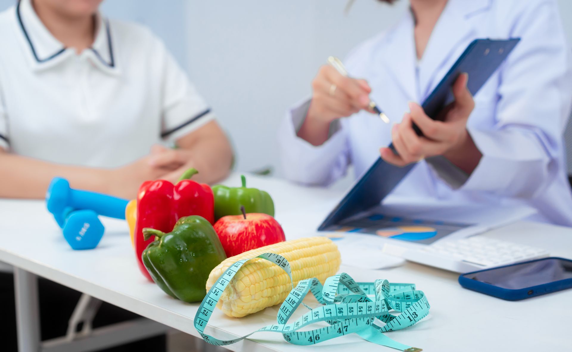 Dietitian consulting with a patient; vegetables, measuring tape, and weights on the table. Dietitian consulting with a patient; vegetables, measuring tape, and weights on the table.
