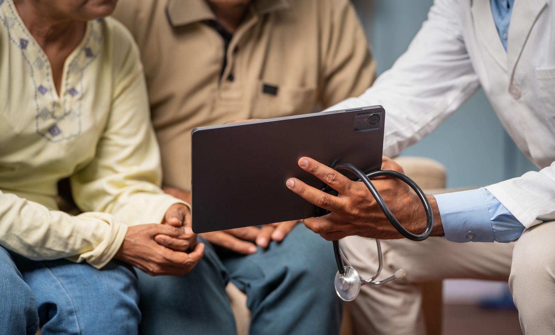 Doctor showing tablet to senior couple, stethoscope visible. Doctor showing tablet to senior couple, stethoscope visible.