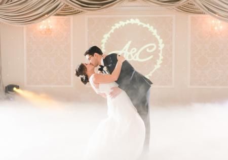 Bride and groom dancing in a fog-filled wedding venue under soft pink lighting