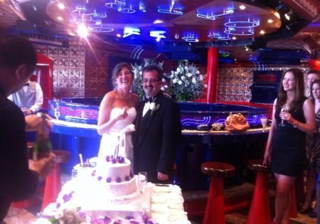 Wedding couple standing by a cake in a colorful nightclub reception hall