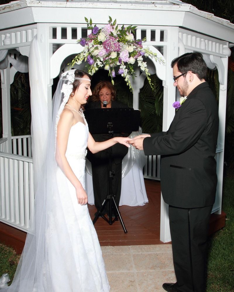 Bride and groom exchanging vows under a floral arch at an outdoor wedding ceremony