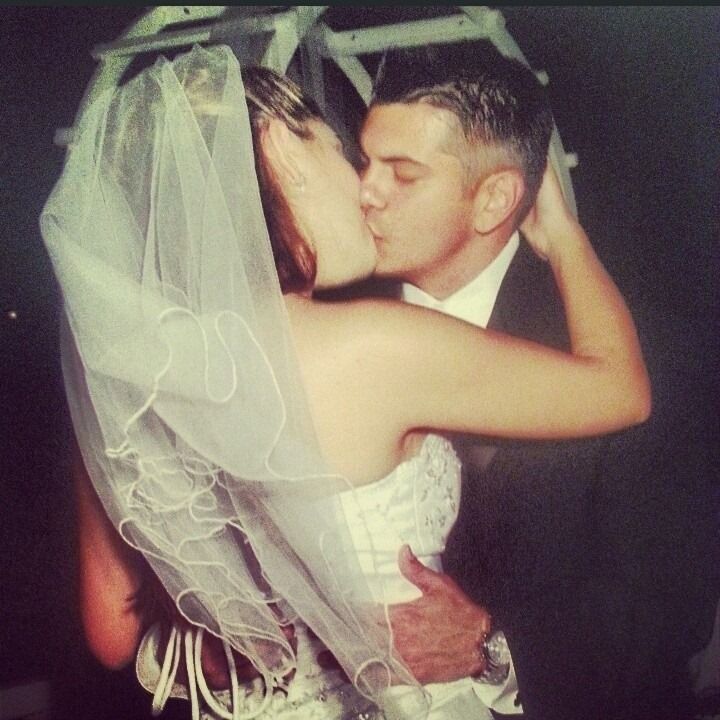 Bride and groom kissing during wedding ceremony, bride in veil and white dress.