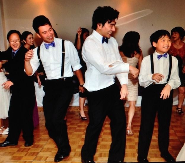 People in white shirts and black pants dancing at a party on a wooden floor