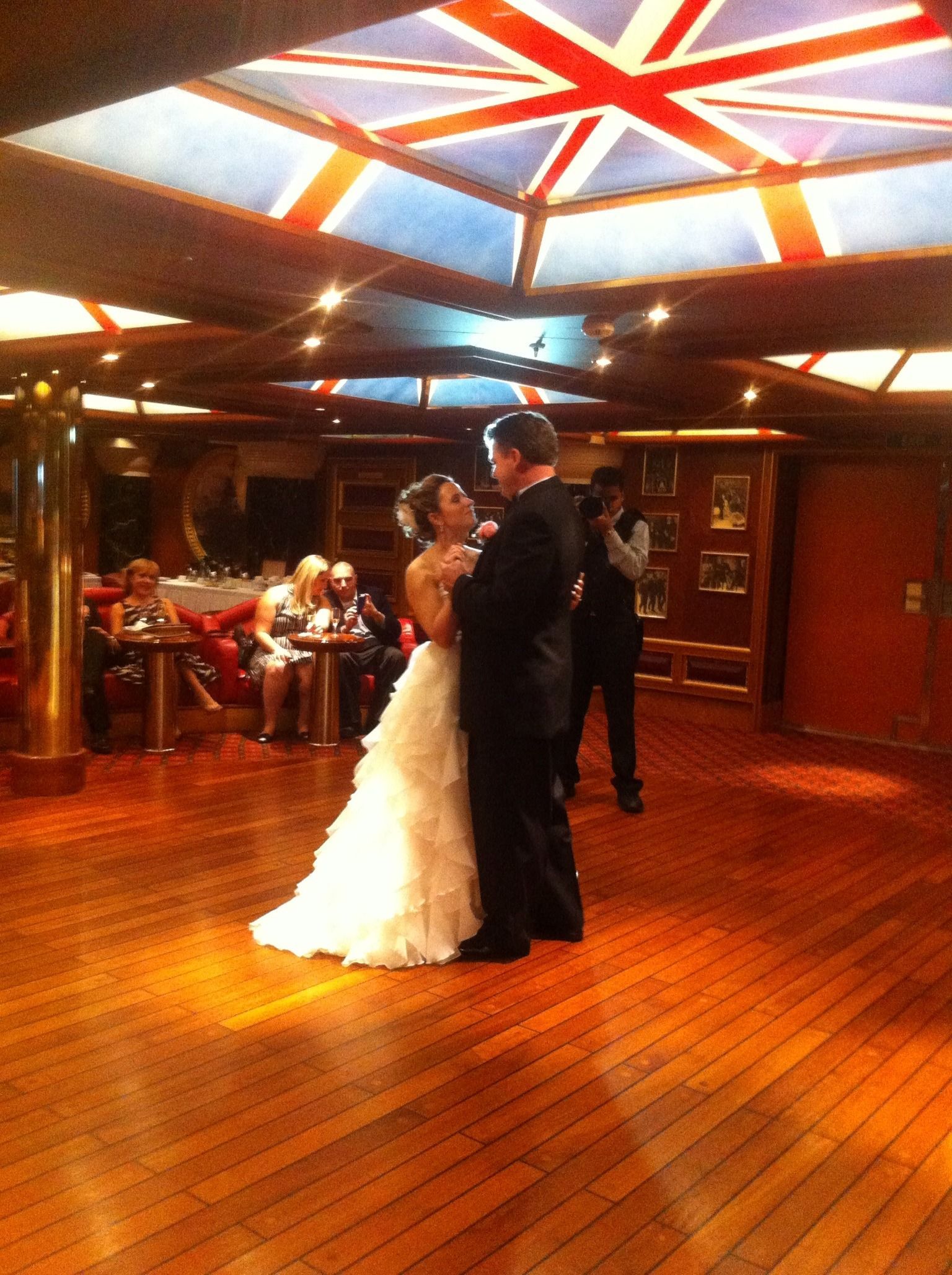 Bride and groom dancing in a wooden-floored reception hall with a star-patterned ceiling