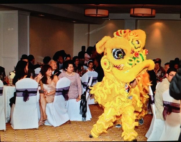 Yellow lion dance costume performing at an indoor banquet with seated guests watching.