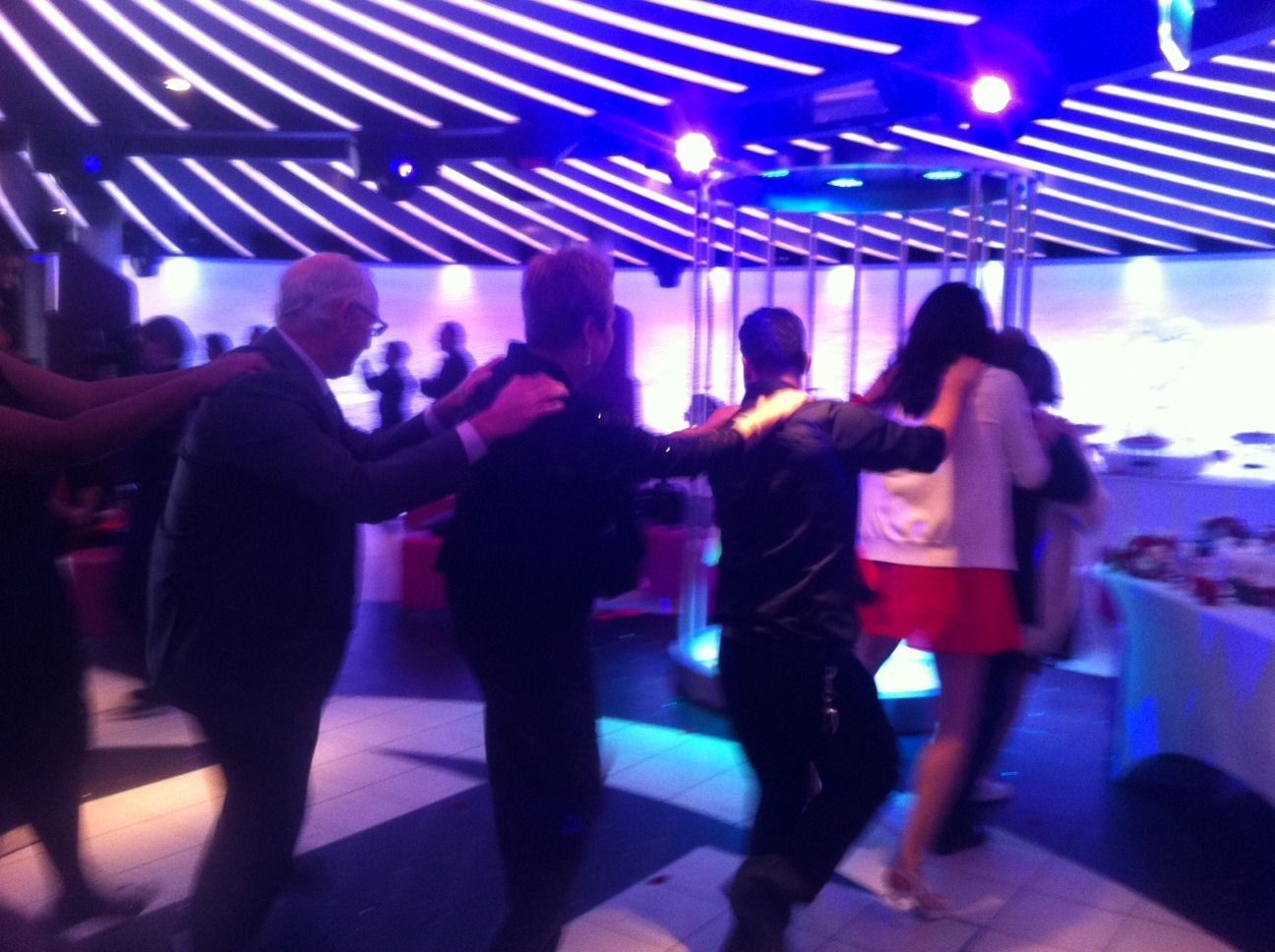 People dancing in a purple-lit nightclub with striped ceiling lights