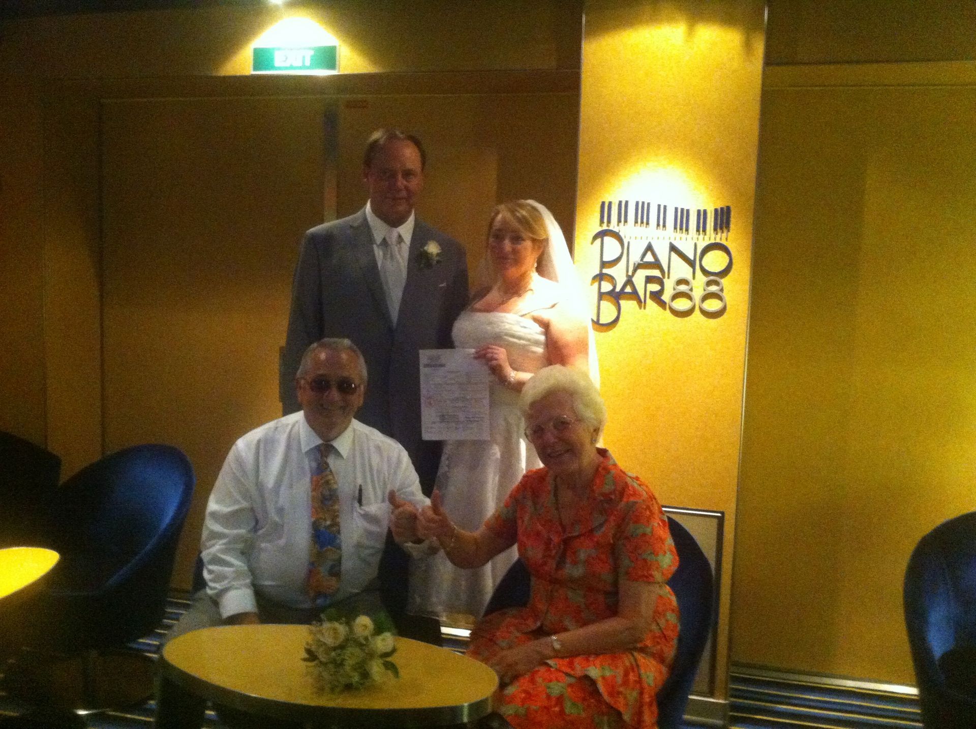 Four people posing in a dimly lit restaurant with a “Piano Bar” sign on the wall