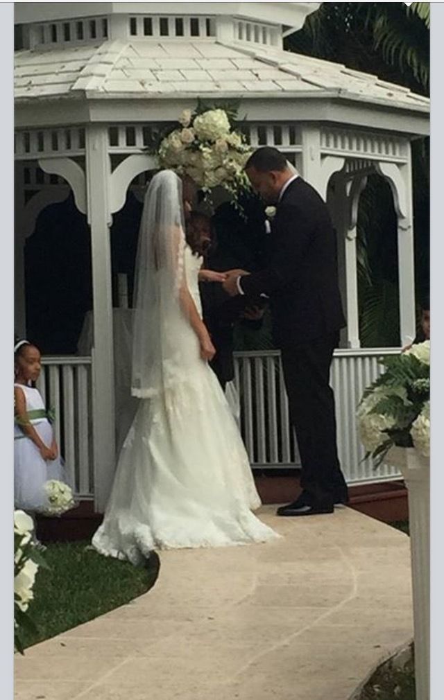 Bride and groom exchanging vows under a white gazebo at an outdoor wedding ceremony