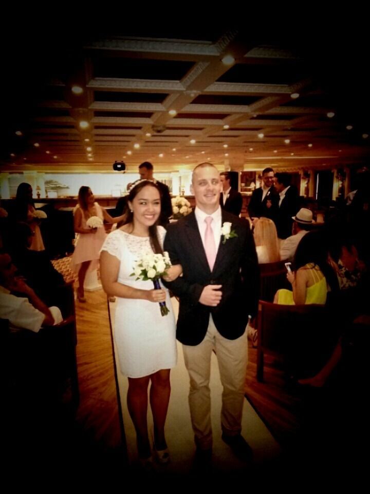 Woman in white dress holding bouquet with man in suit at an indoor formal event