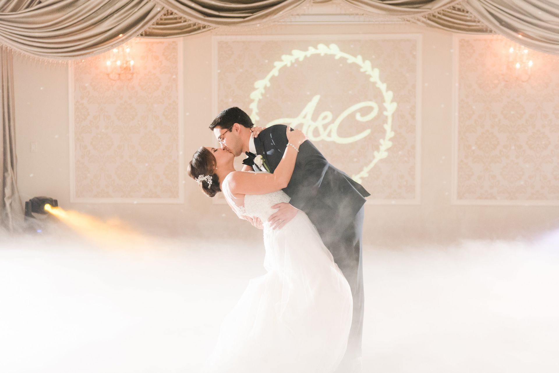Wedding couple dancing in a fog-filled ballroom under soft lights