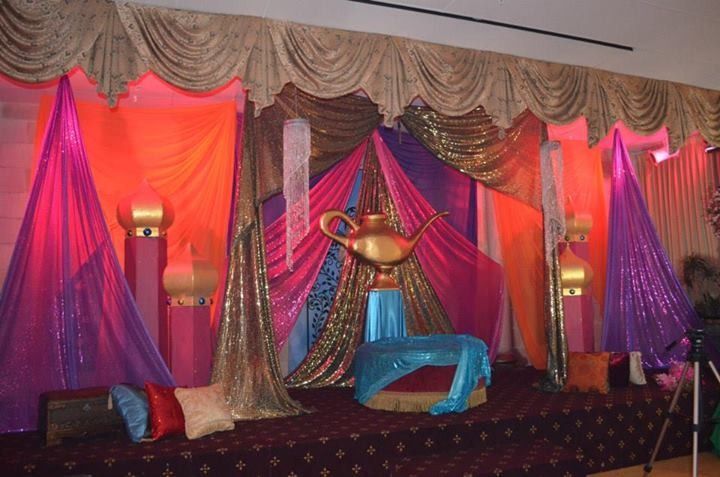 Colorful stage backdrop with draped pink, purple, and gold fabrics and seating in front