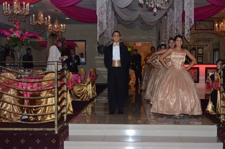 Formal event with two people in elegant gowns and a man standing on a decorated stage