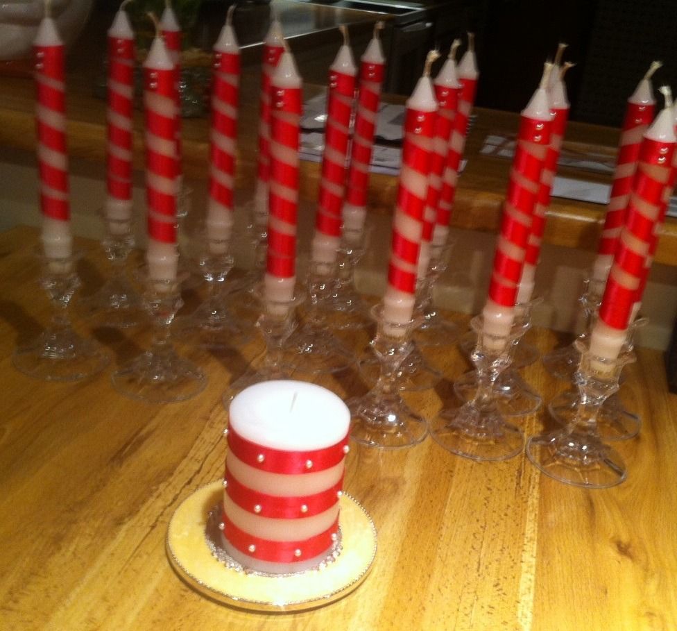 Red and white striped candles in glass holders on a wooden table, with one candle in the foreground.