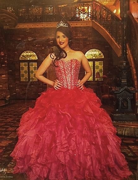 Woman in a bright pink ball gown posing in an ornate, dimly lit hall
