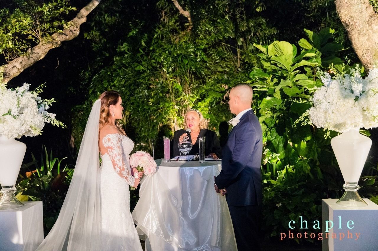 Bride and groom at a candlelit outdoor wedding ceremony beneath a floral arch
