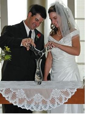 Bride and groom pour champagne into a tower glass at their wedding reception