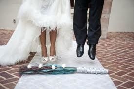 Bride and groom jumping over a ceremonial broom on a wedding floor