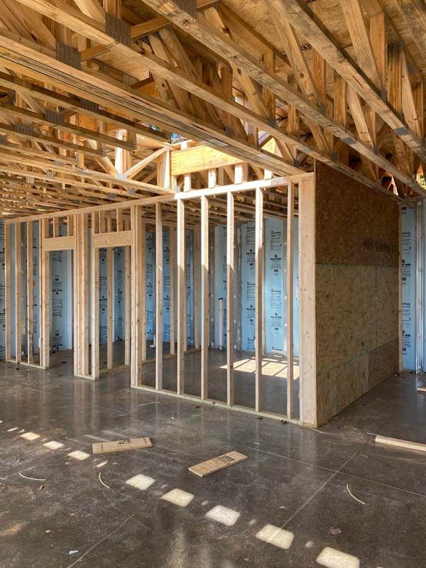 Interior view of a building under construction, showing wooden framing and concrete floor.