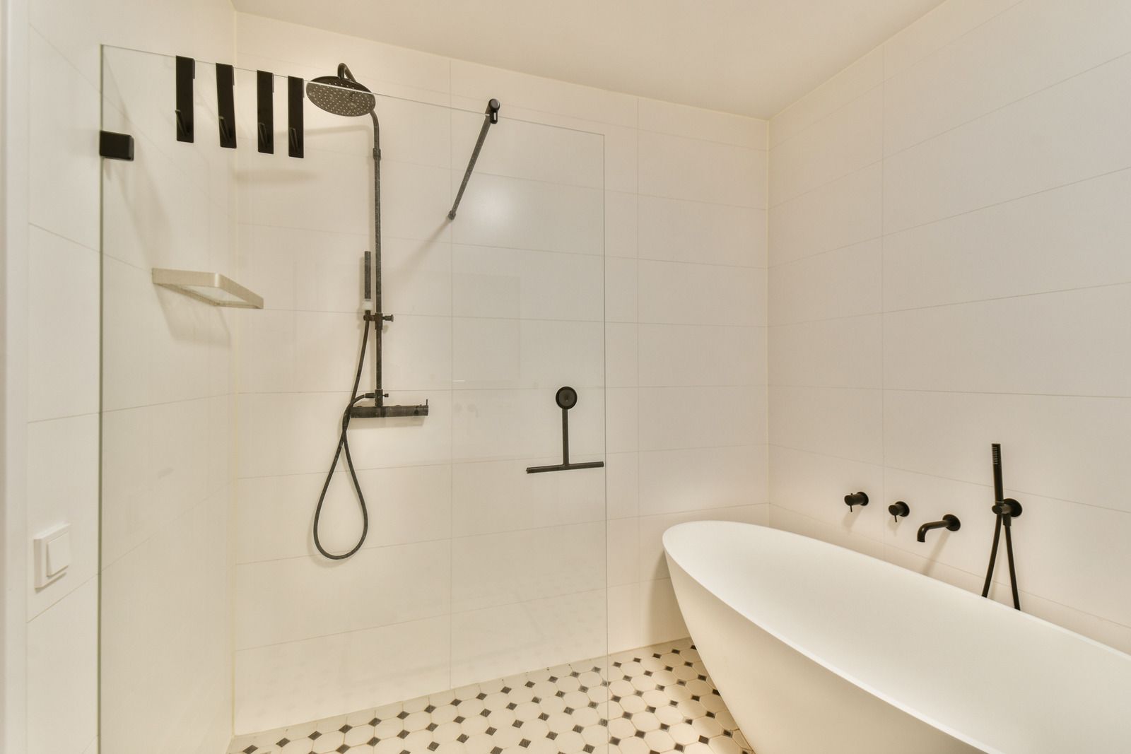 Modern white bathroom with a shower, freestanding tub, and black fixtures.
