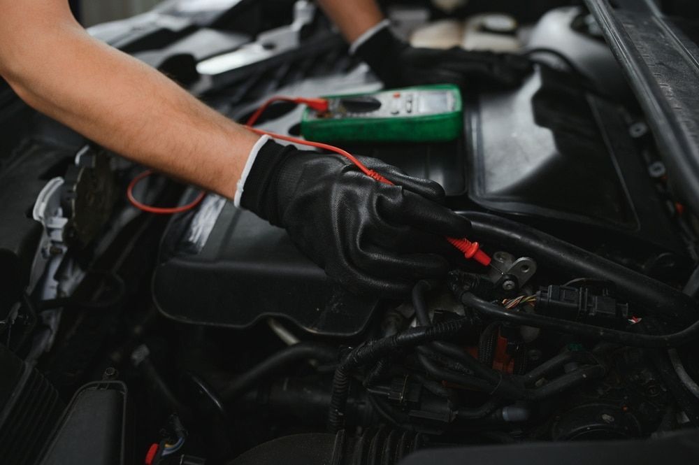 A Man is Working on a Car Engine with a Multimeter — Innisfail Auto Electrics Pty Ltd in Mundoo, QLD
