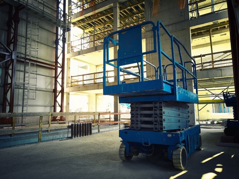 A Blue Scissor Lift is Parked in a Large Building under Construction — Innisfail Auto Electrics Pty Ltd in Mission Beach, QLD