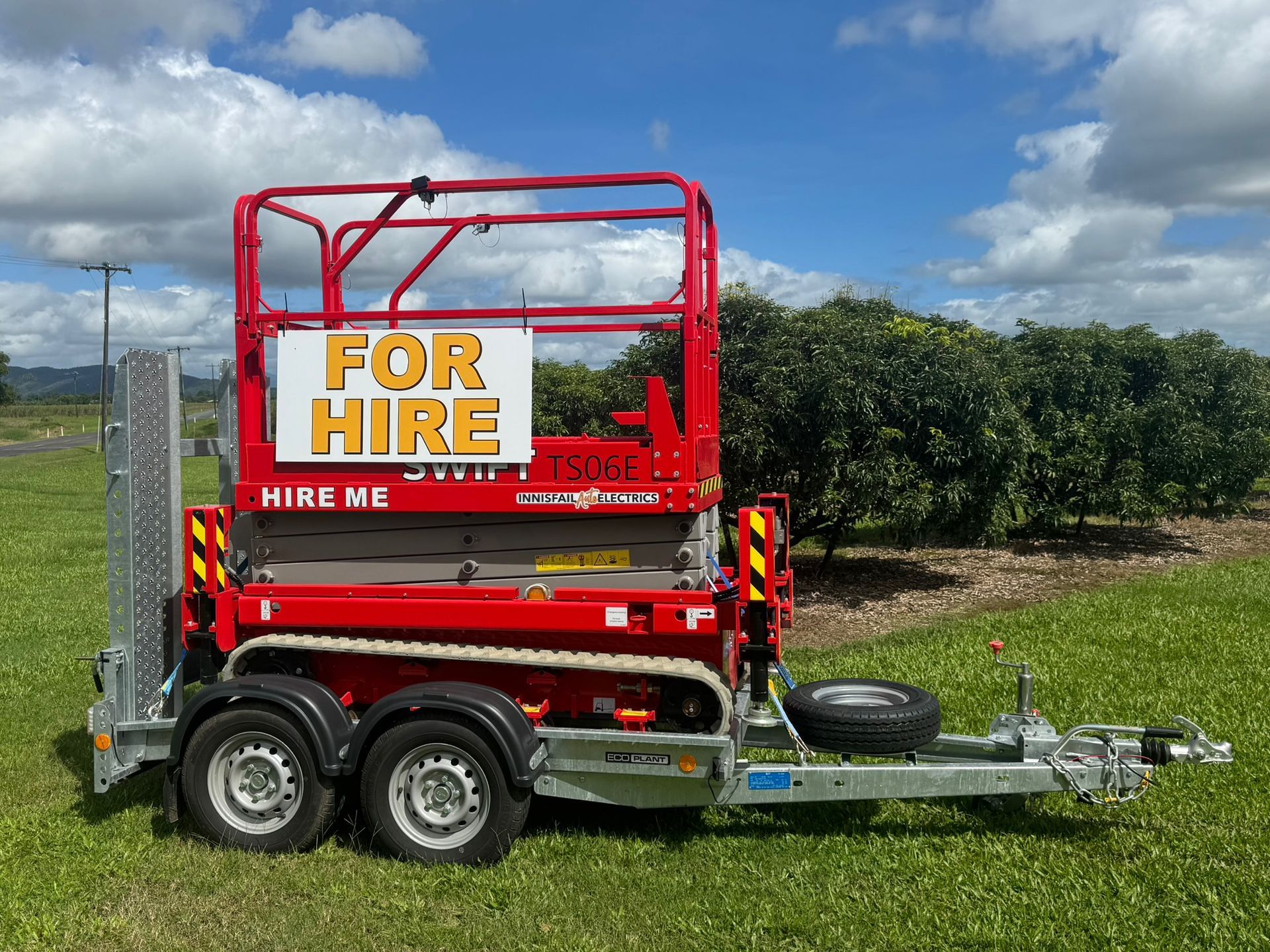 A Red Scissor Lift is on a Trailer in Front of a Building — Innisfail Auto Electrics Pty Ltd in Mundoo, QLD