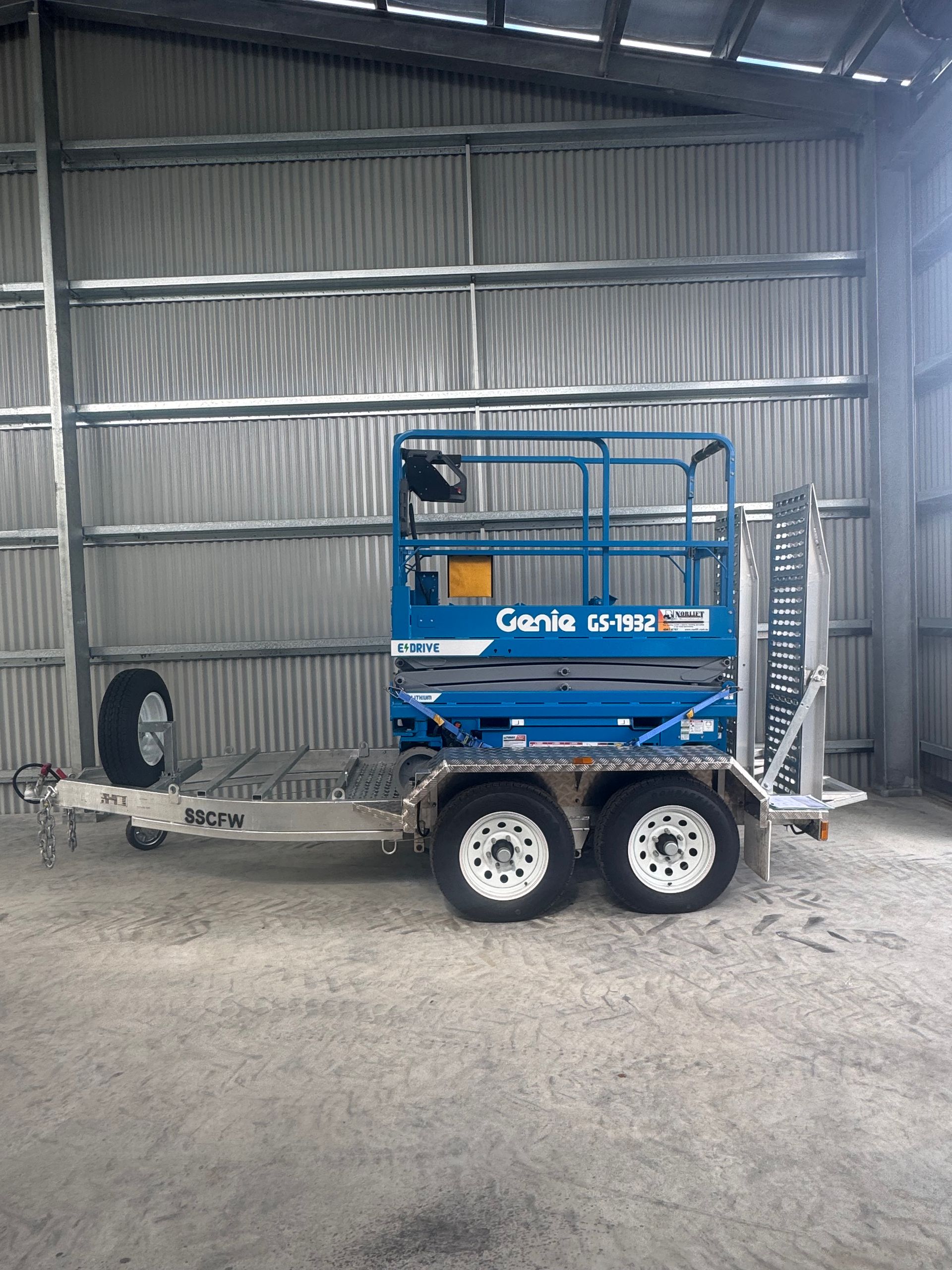 A Red Scissor Lift is Parked in Front of a Building — Innisfail Auto Electrics Pty Ltd in Mundoo, QLD